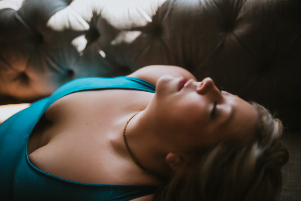 woman in teal outfit with her head tilted back and relaxed 